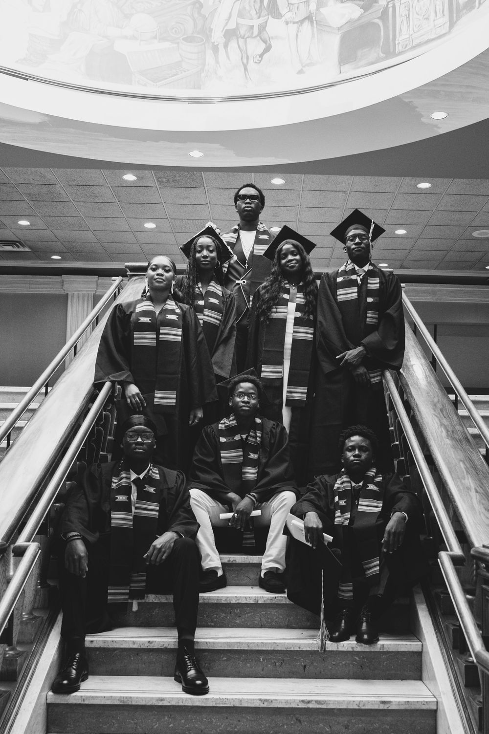 Graduates in ceremonial attire posing on stairs in a creative sequence of photos.