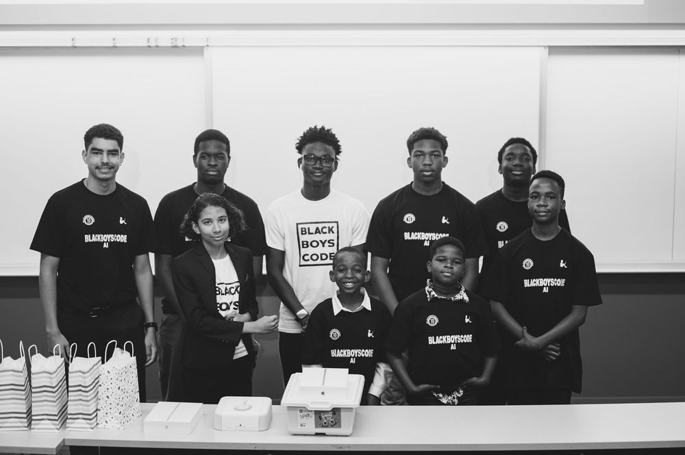 Group wearing matching black t-shirts posing together at an event.