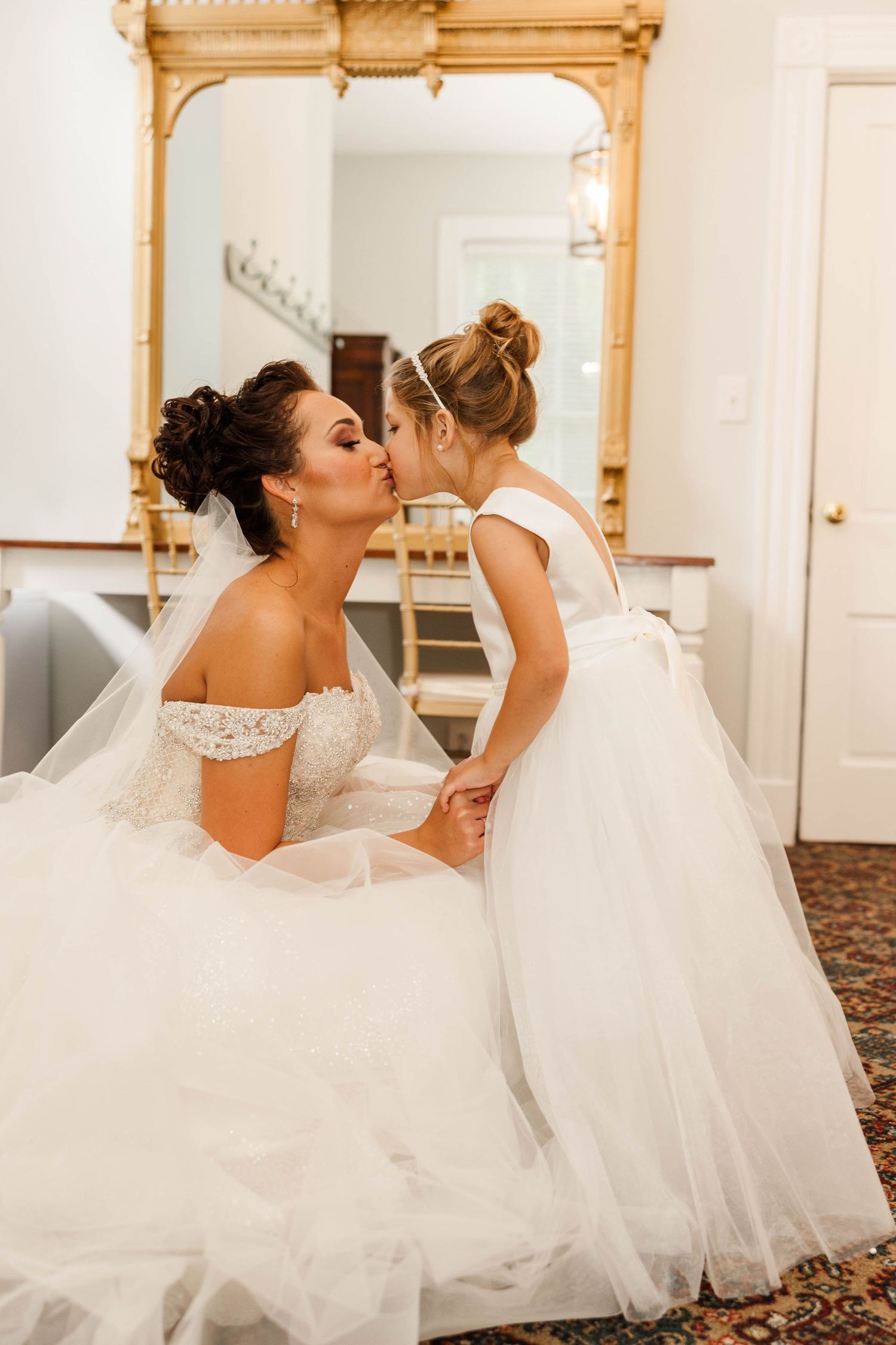 Sweet moment between bride and flower girl in matching white dresses.
