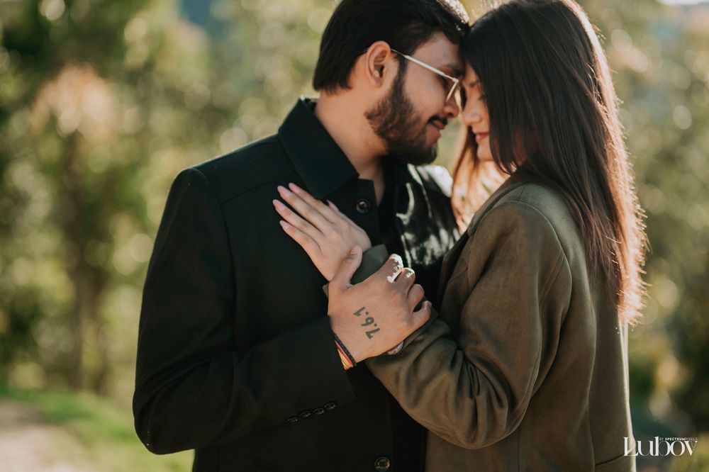 Romantic couple embracing outdoors during golden hour in a natural setting with sunlit trees in background.