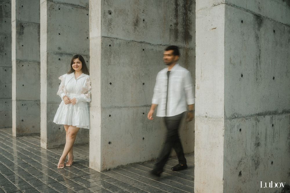 Two people in modern attire walking through a minimalist concrete corridor.