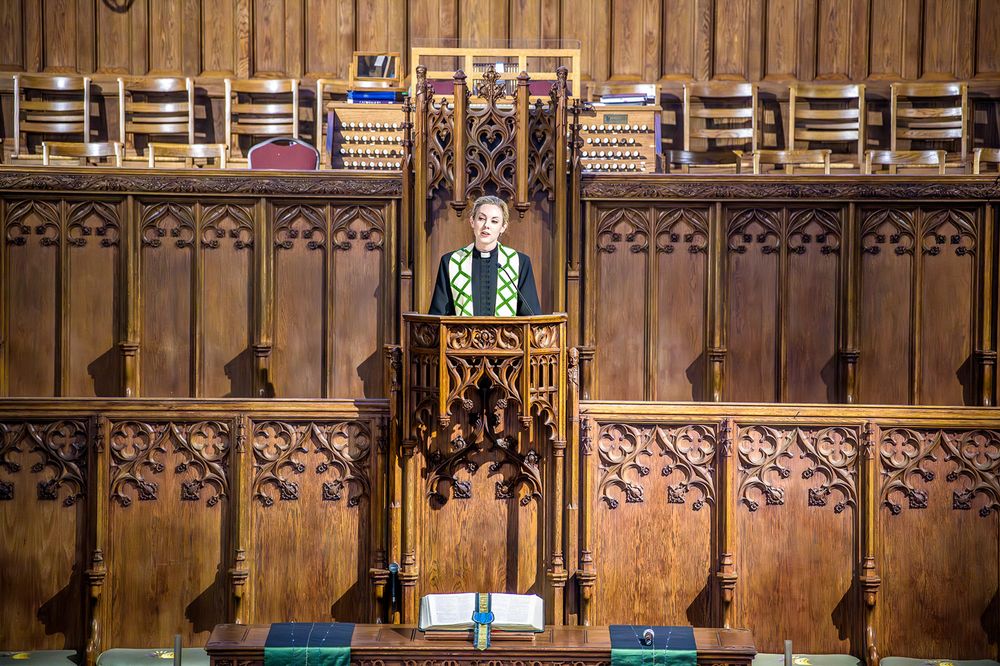 An ornate wooden cathedral pulpit stands against an intricately carved Gothic wall with decorative panels.
