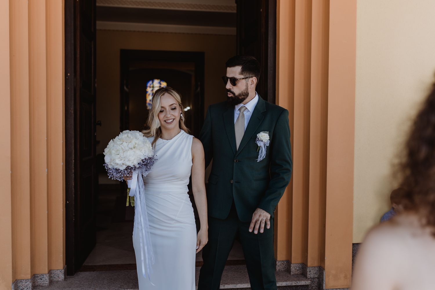 Newlywed couple standing in elegant hallway with orange walls.