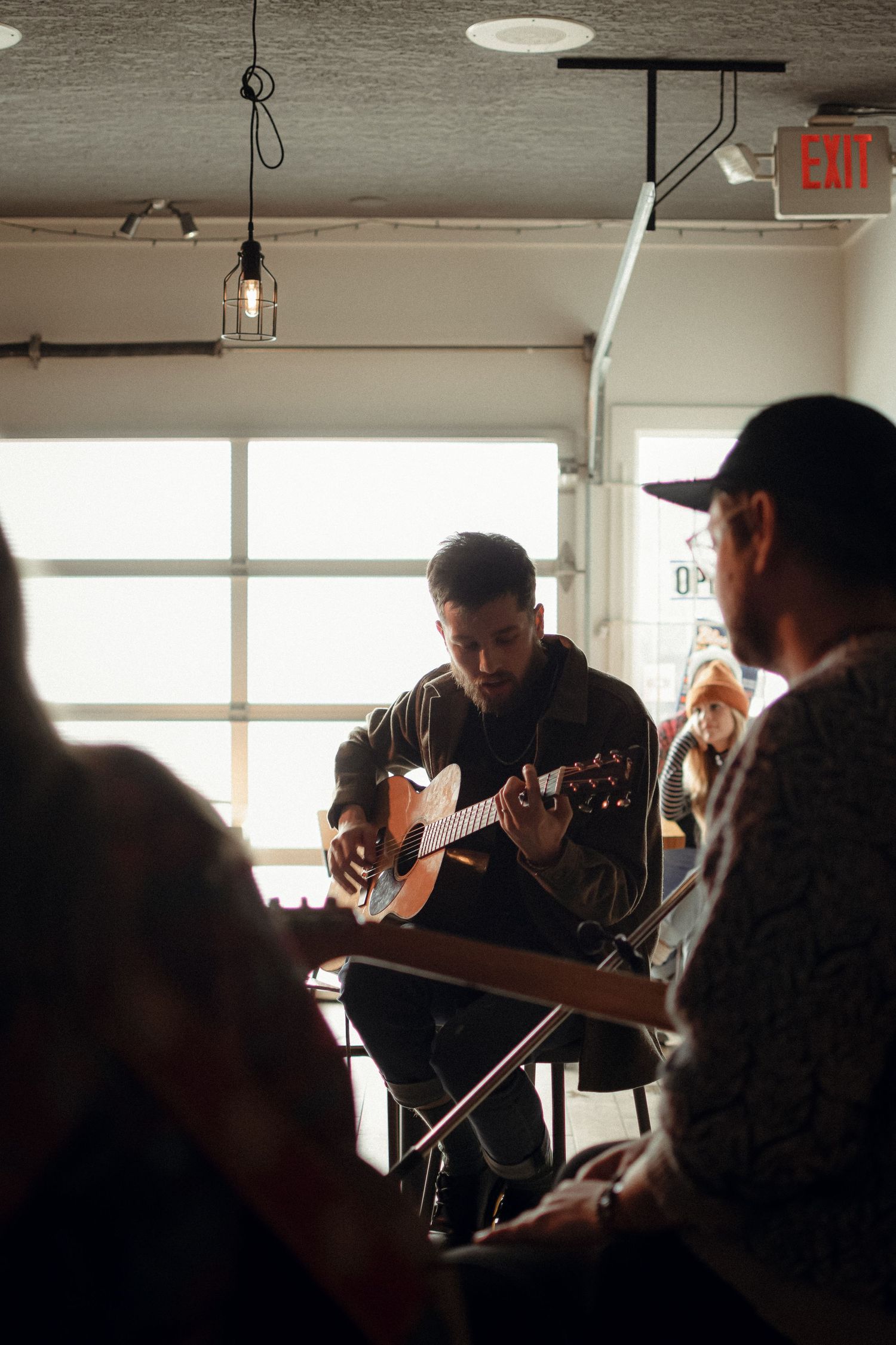 Musician playing acoustic guitar during an intimate indoor performance.