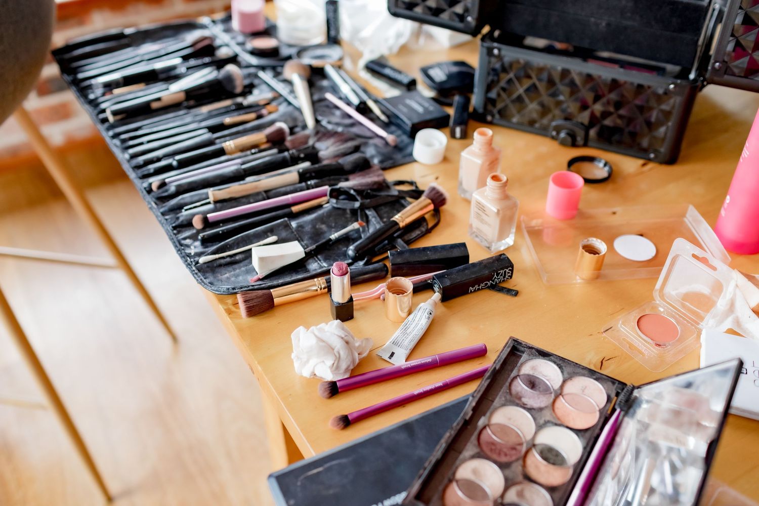 Professional makeup brushes and cosmetics arranged on wooden surface during wedding preparation.