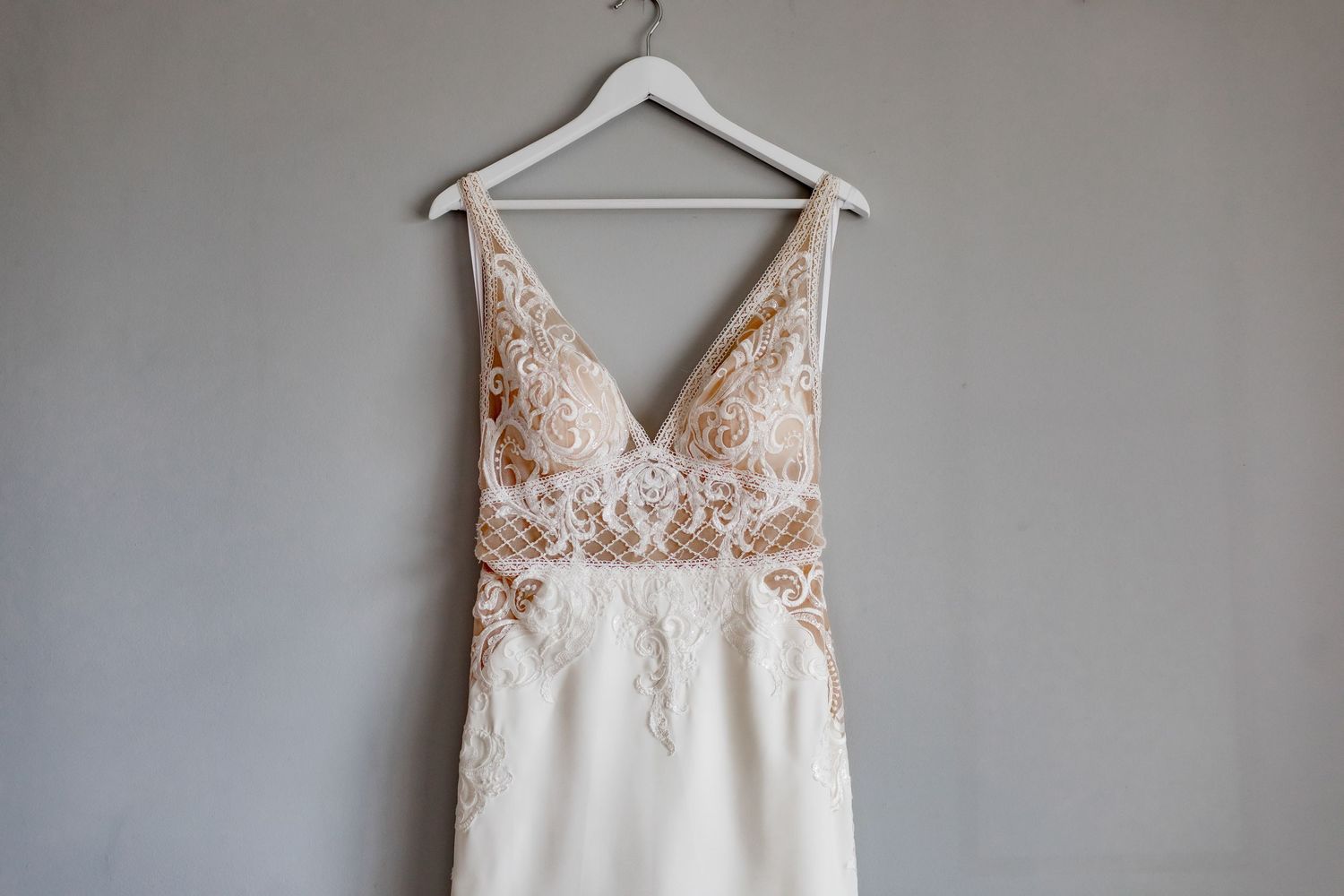 Close-up of wedding dress bodice showing intricate lace detailing and V-neckline.