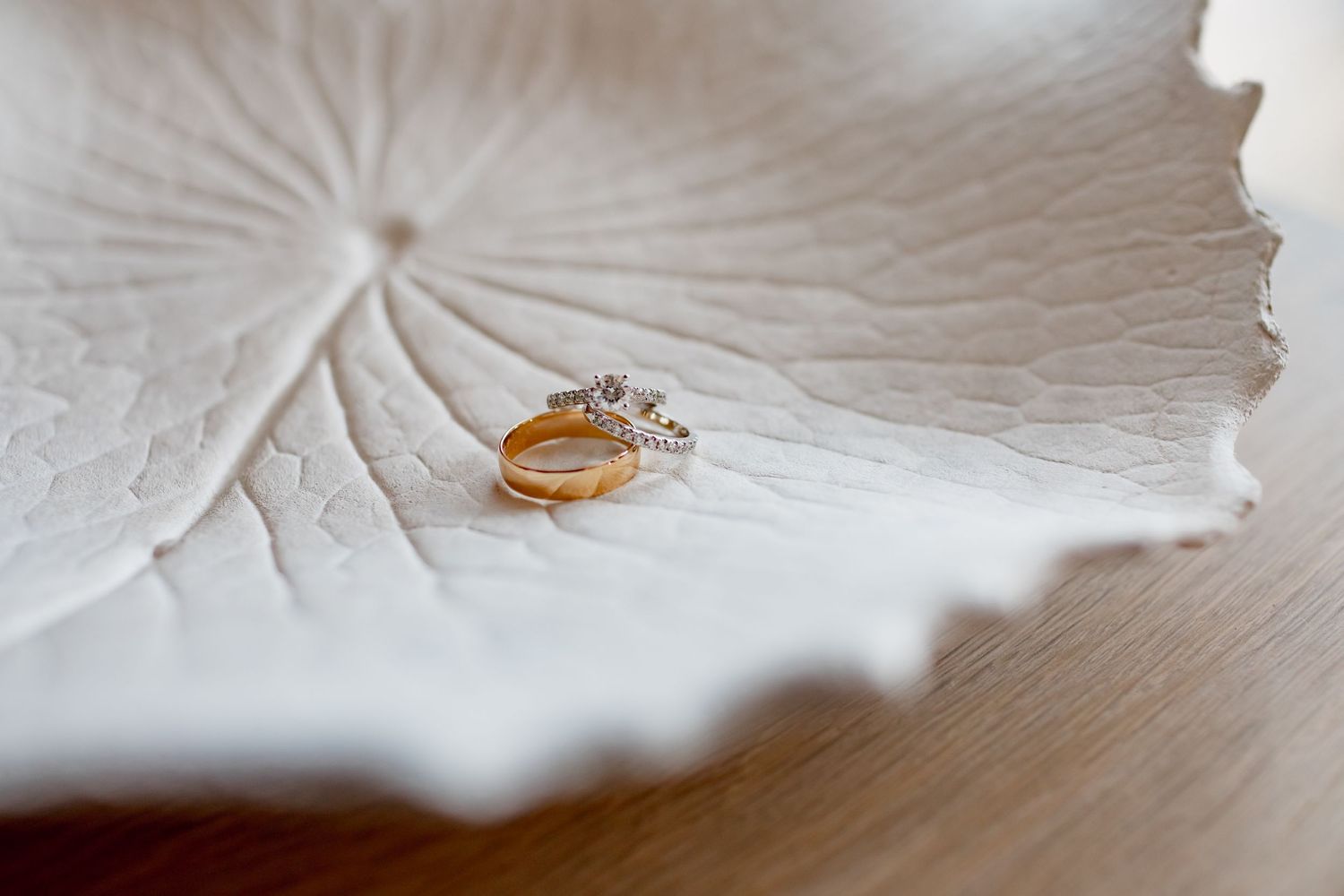 Wedding ring photographed on a white decorative plate with textured details.