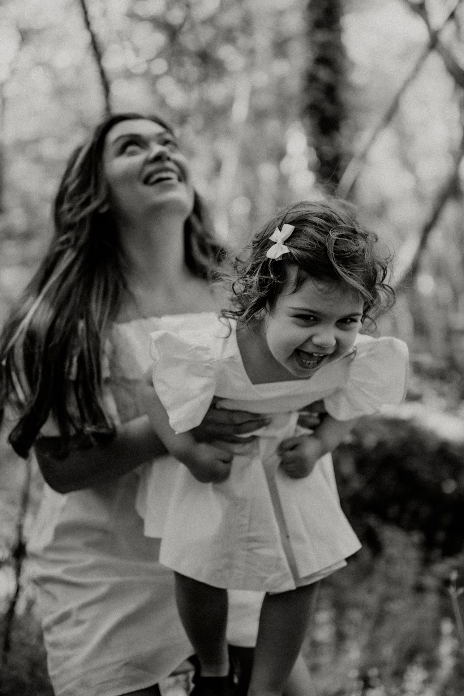 Black and white photo capturing a moment of pure joy and laughter in the woods.