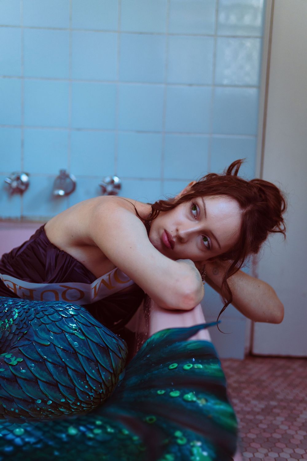 A person in a shimmering teal dress lies on the floor in a dreamy artistic photo series.