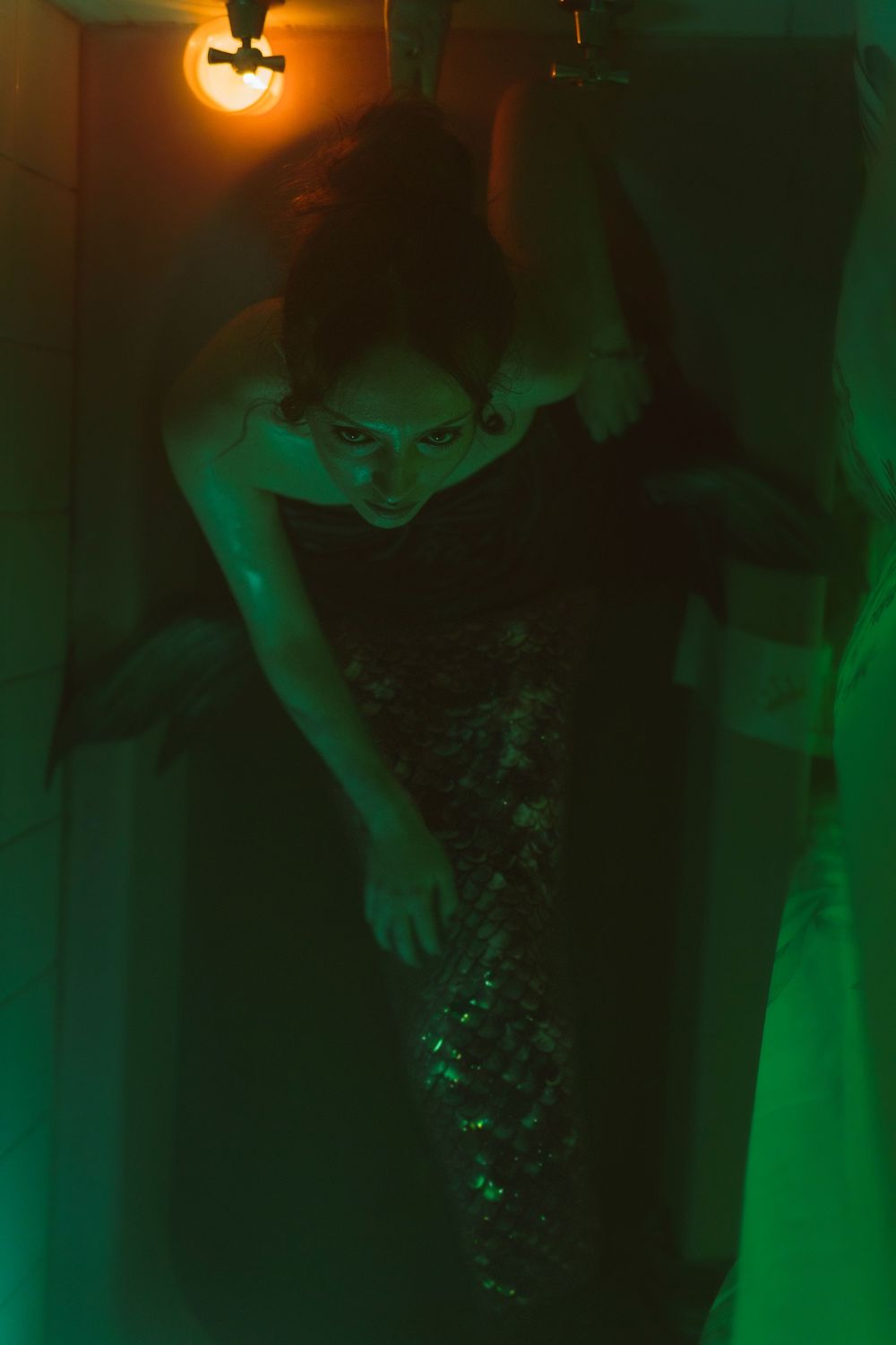 Atmospheric green-lit nightclub scene with dancing figures silhouetted against dark background.
