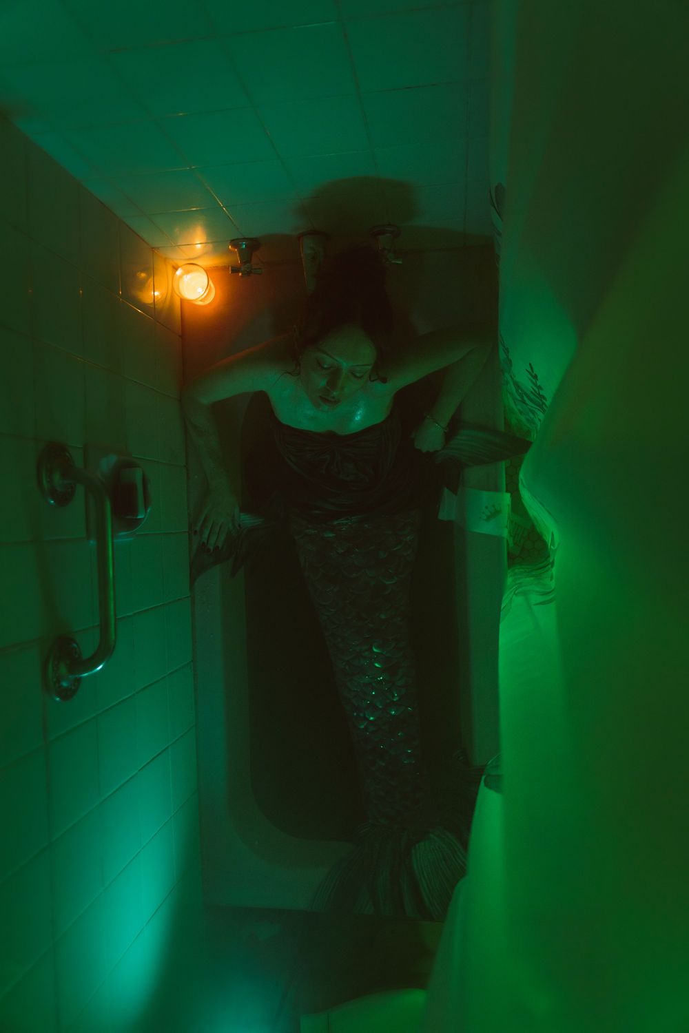A spooky green-lit hallway with a glowing orange light fixture and dark silhouette creating an eerie atmosphere.