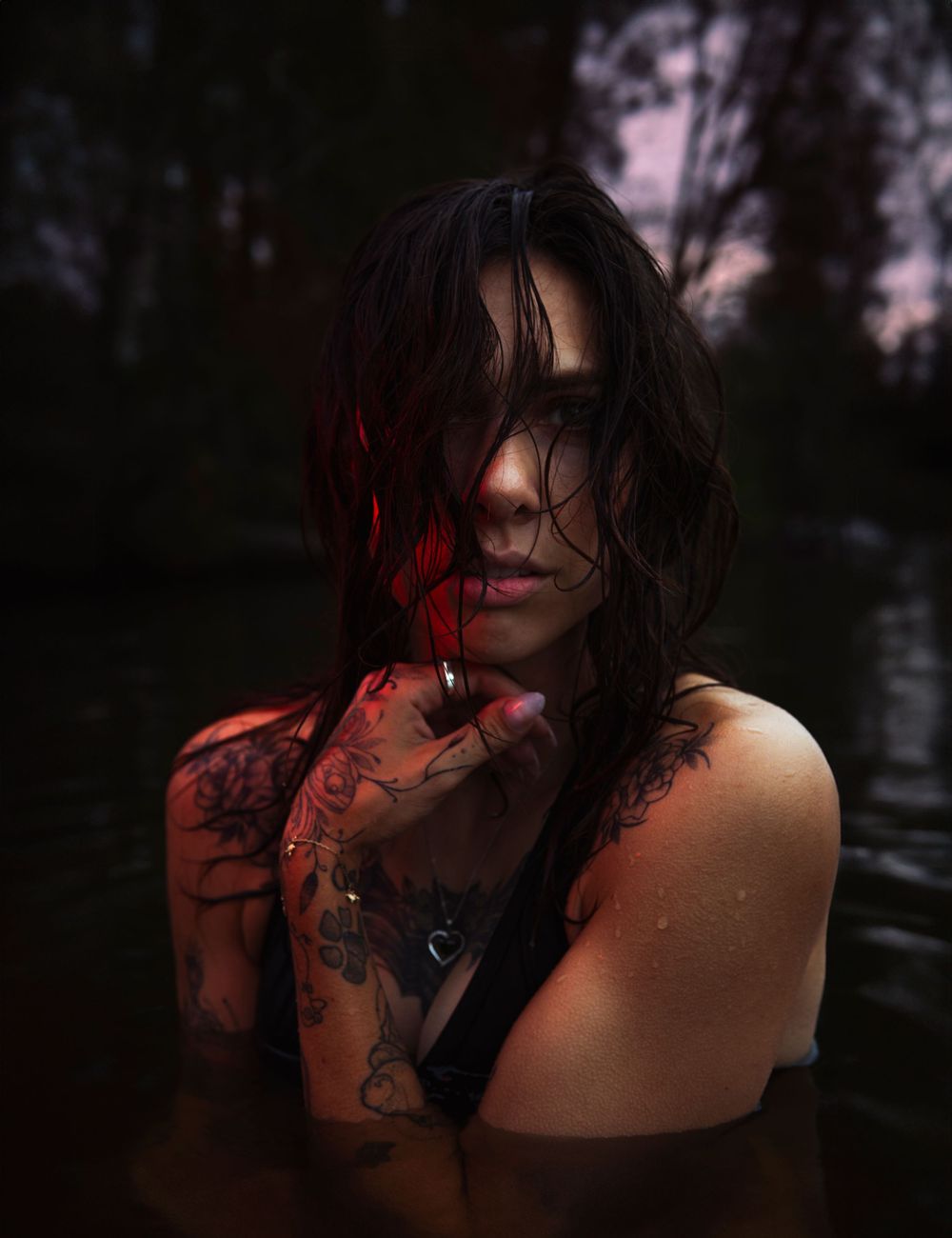 Artistic dark portrait with red lighting and water droplets creating dramatic mood.