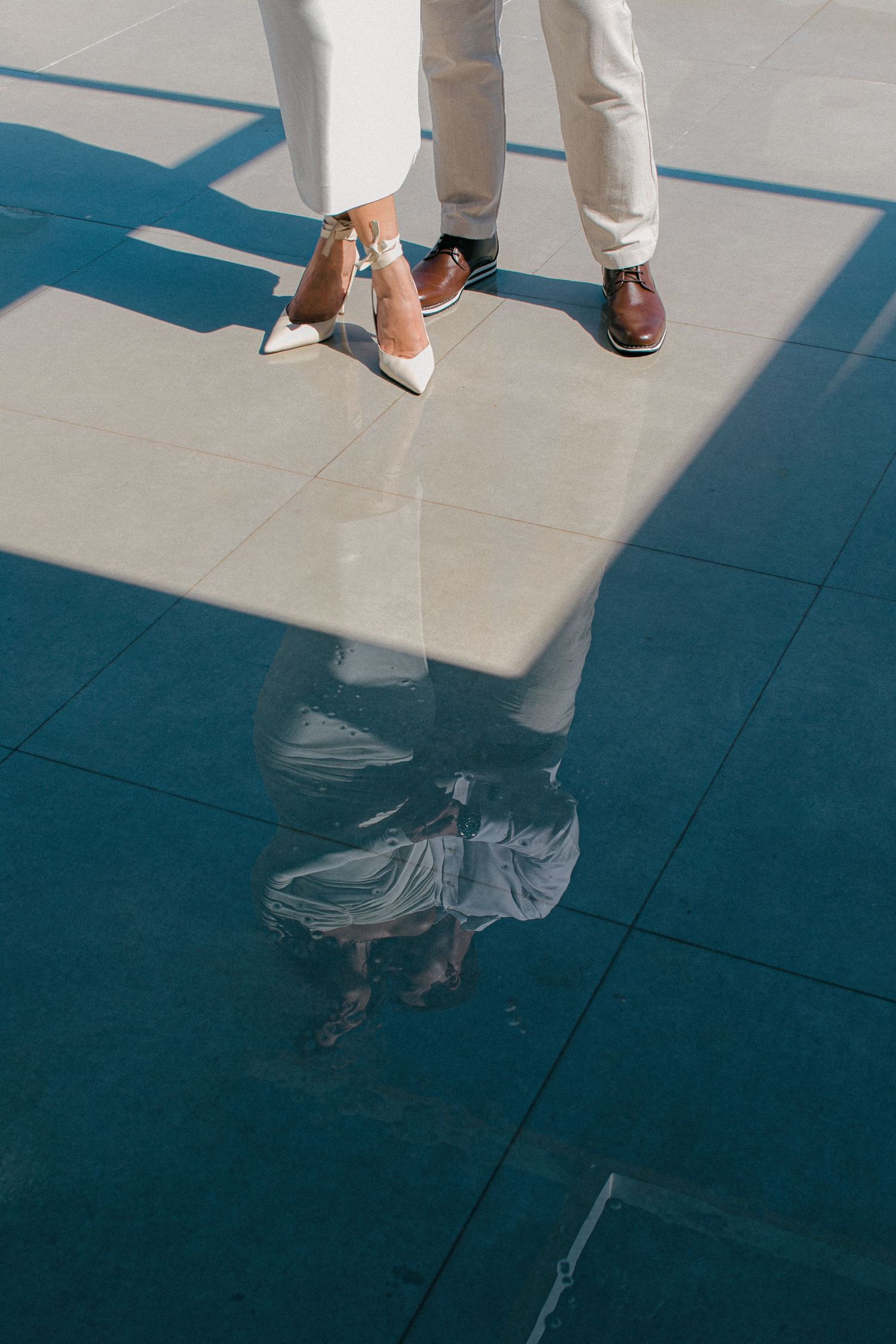 Close-up of formal shoes and their reflection on a polished blue floor.