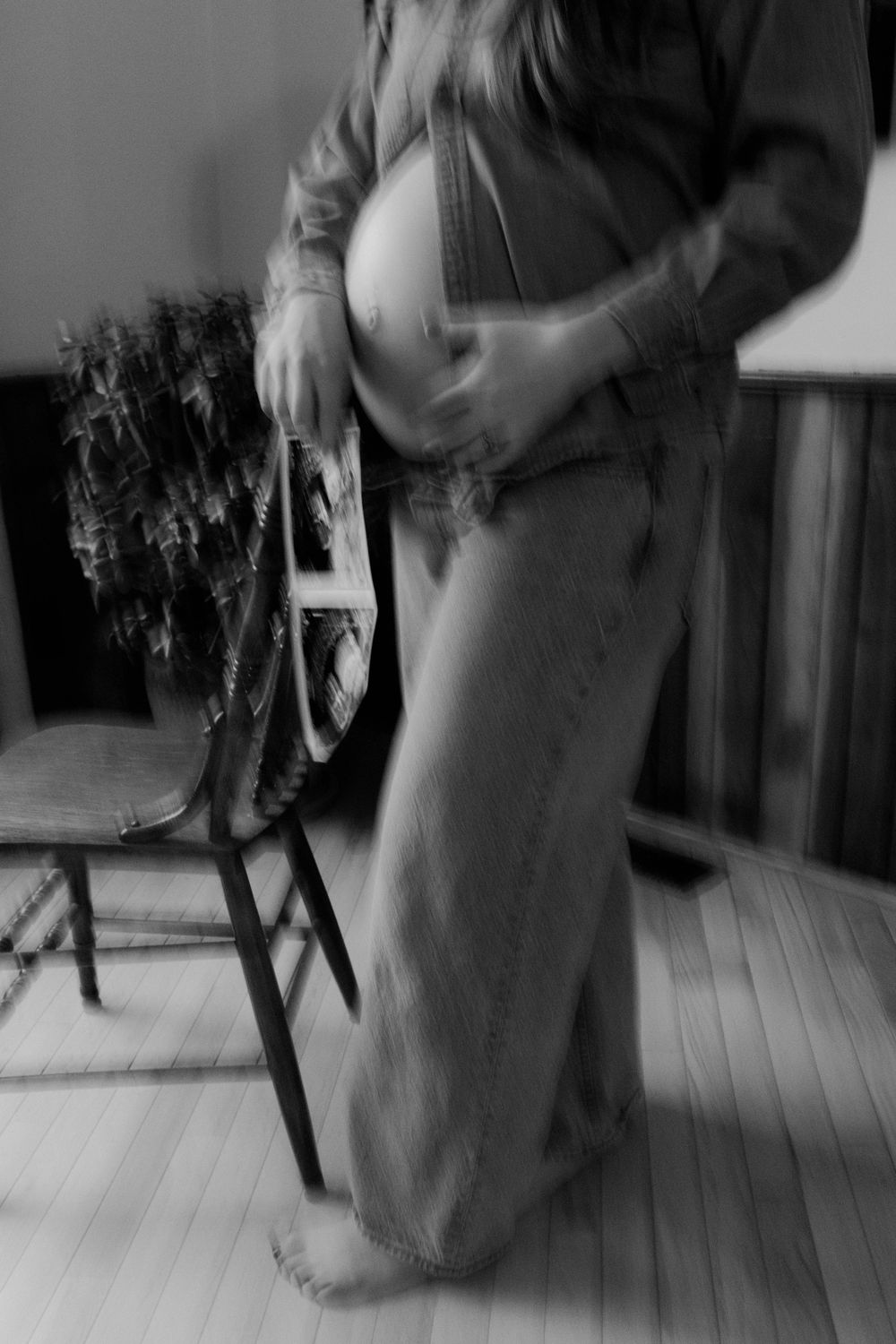 A black and white sequence of motion blur photographs showing a person twirling in a long dress on a wooden floor.