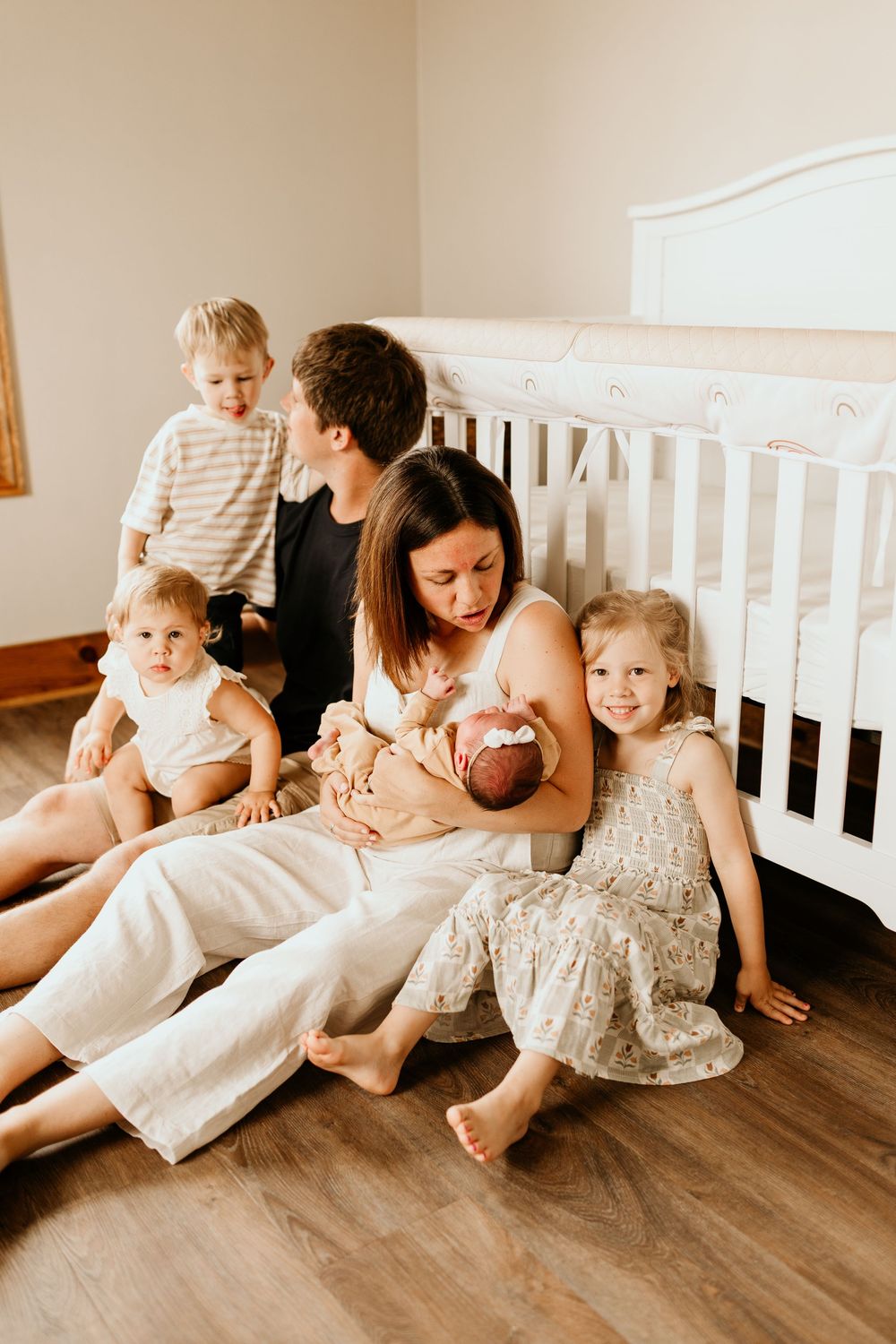 A heartwarming family scene with parents and children lounging together on wooden floors in soft neutral tones.