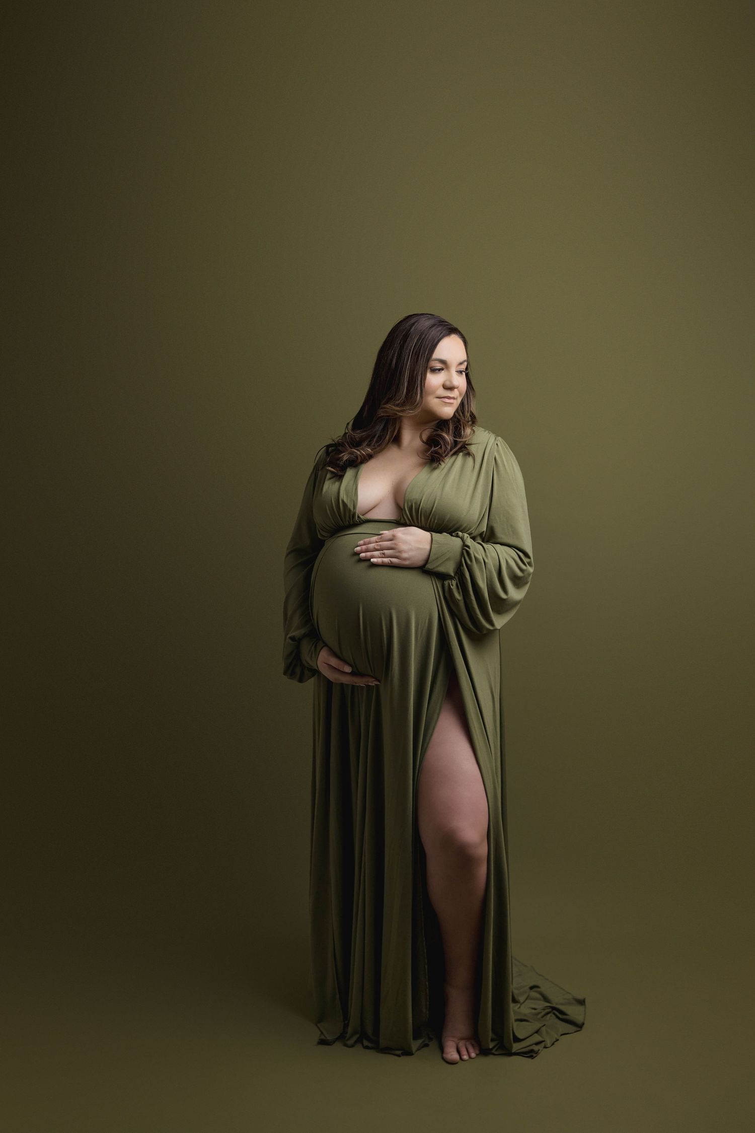 Woman in deep neck line deep green gown with large slit up thigh.