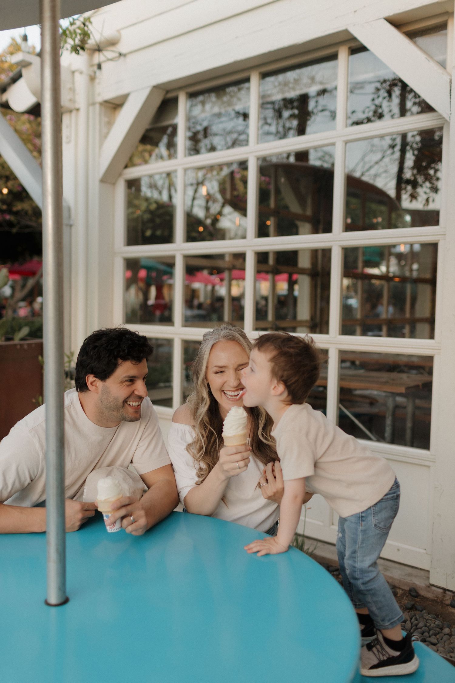 Family sharing joyful moment at outdoor cafe with blue table.