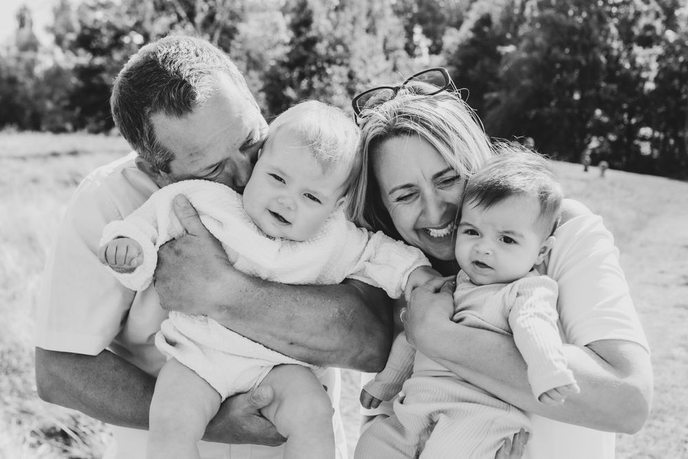 Black and white portrait of a family lounging together outdoors on a sunny day.
Suffolk Family photos. Beckie Egan Photography.