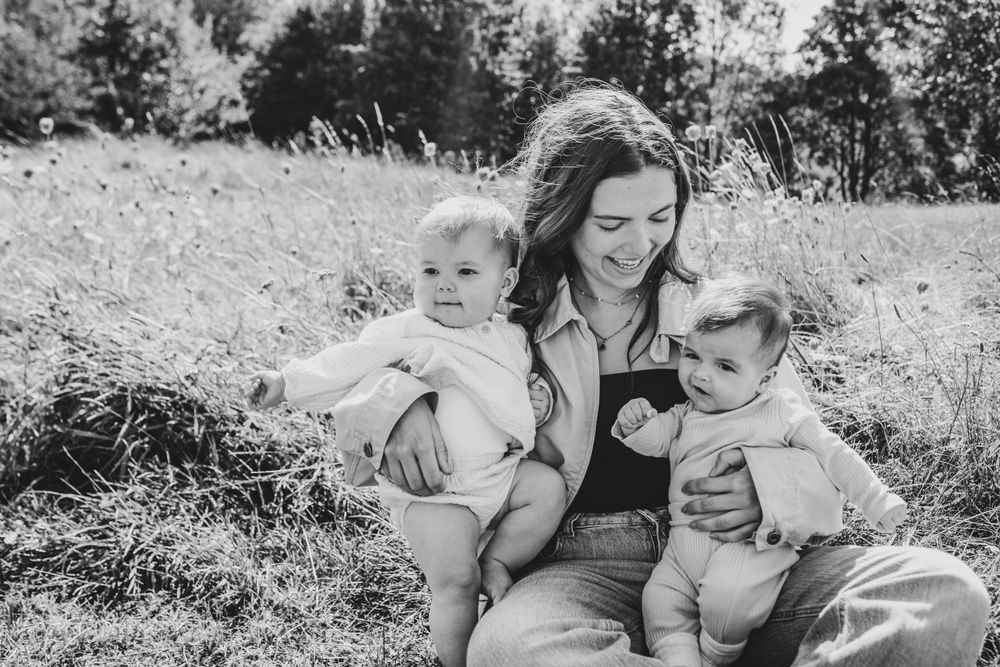 Black and white photograph of a tender moment between parent and children in a meadow.
Suffolk Family photos. Beckie Egan Photography.