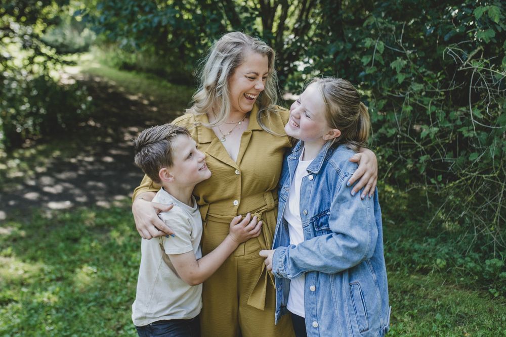 A candid moment of joyful laughter shared between Parent and her children outdoors in a garden setting.
Suffolk Family photos.