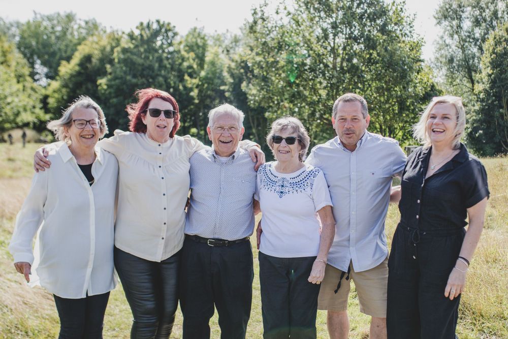Family group of six people smiling together in sunny outdoor setting.
Suffolk Family photos. Beckie Egan Photography.