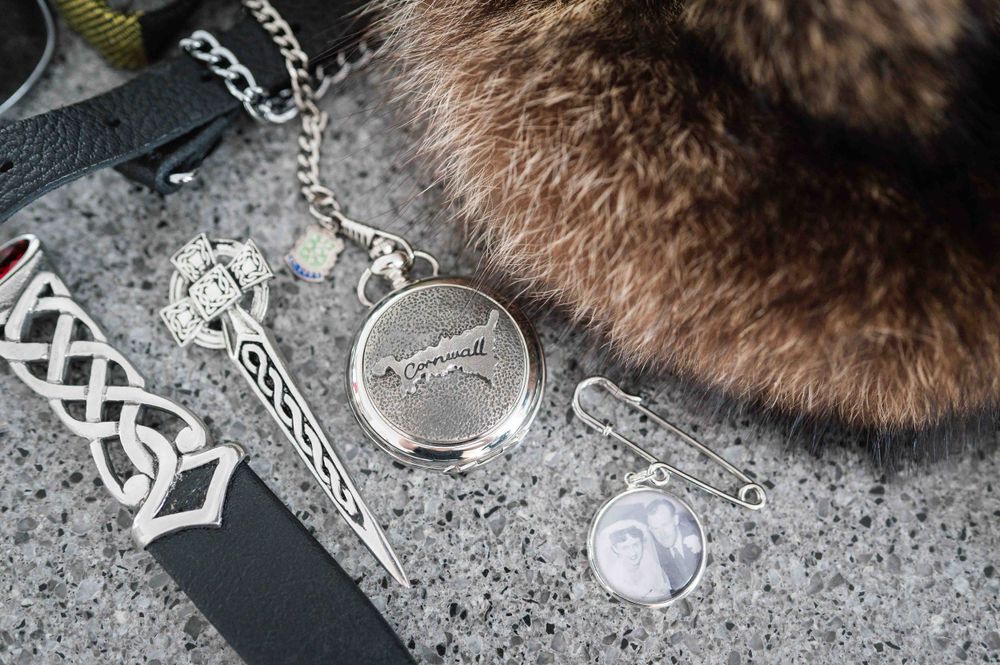 Silver pendant necklaces and chained accessories displayed on a gray speckled surface next to brown fur texture.