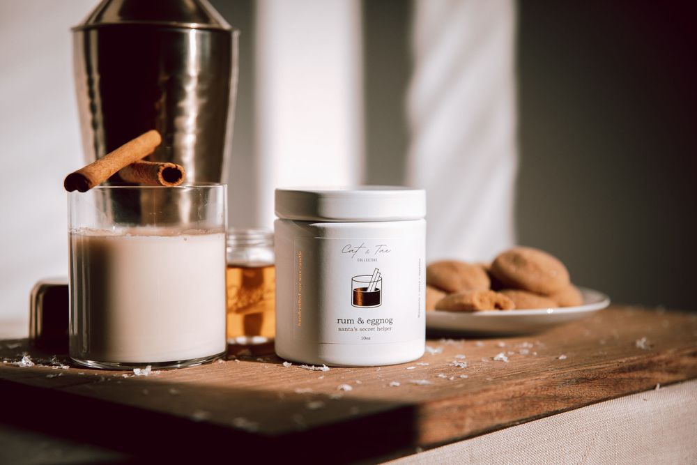 Cozy coffee scene with cinnamon sticks, white canister, and cookies on rustic wooden board.