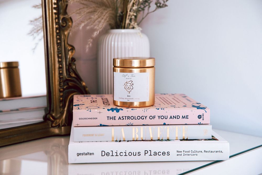 Books and decorative vase arrangement on white surface with gold accents.