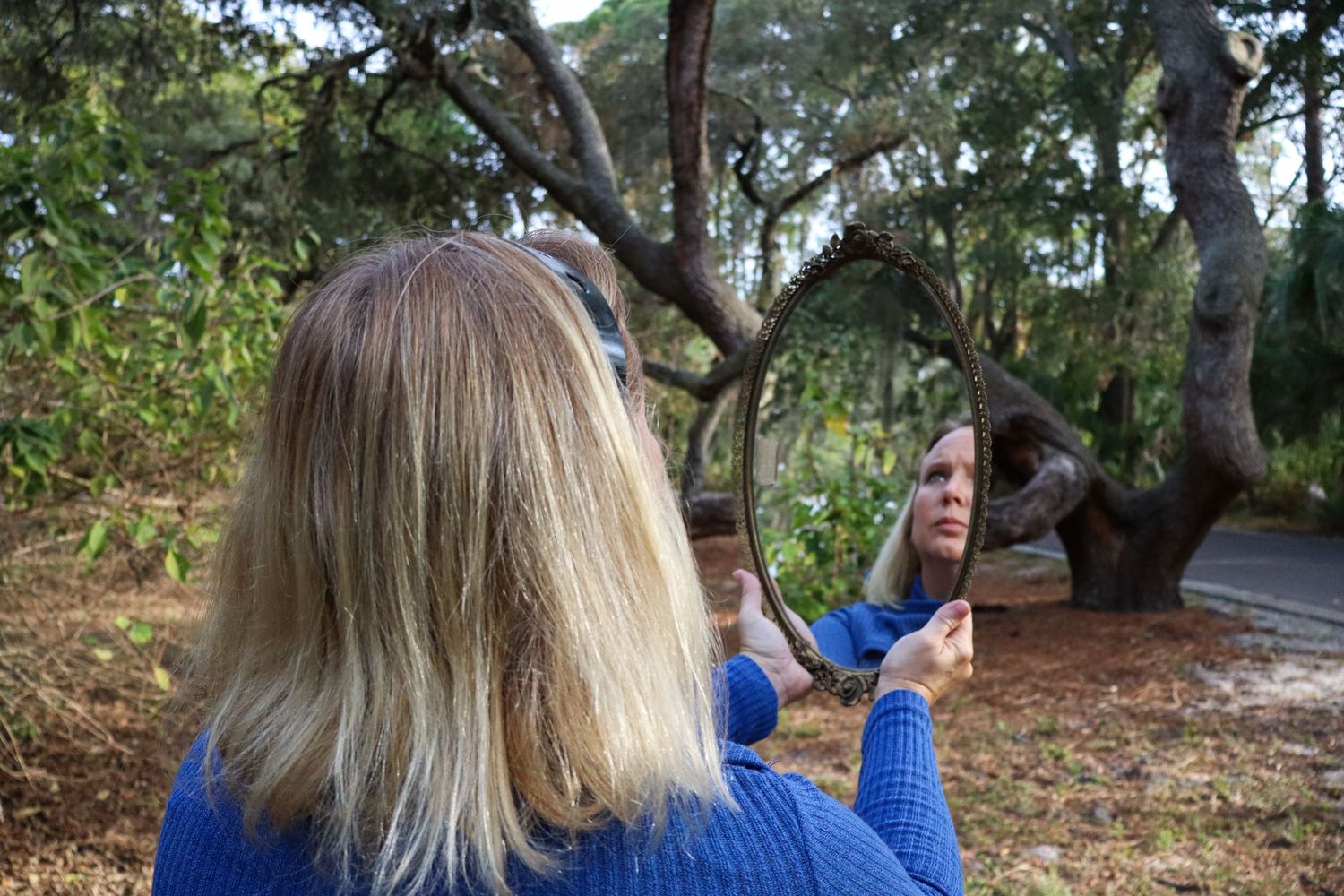The reflection of Heather's face through an antique mirror in a forest guides you to connect with the local photographer