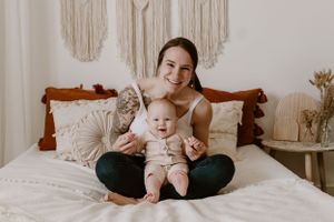 New parents posing together in a light and airy studio, mother, father, and newborn baby, smiling and snuggling