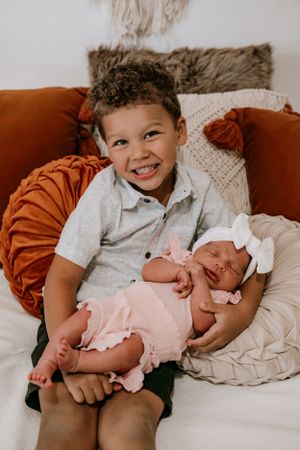 Family of four posing together in a light and airy studio, mother, father, and children, smiling and snuggling