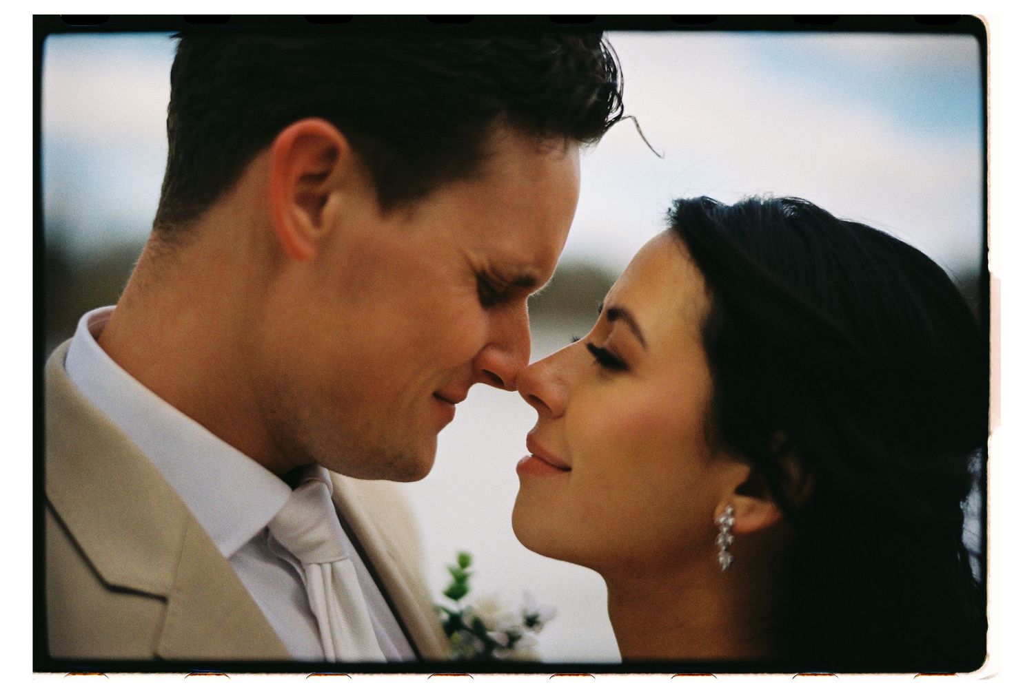 A romantic close up photo of a couple about to kiss at their wedding outdoors.