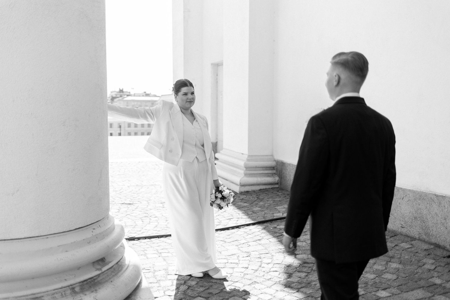 A classic black and white wedding photo taken at Tuomiokirkko with elegant white columns in the background.