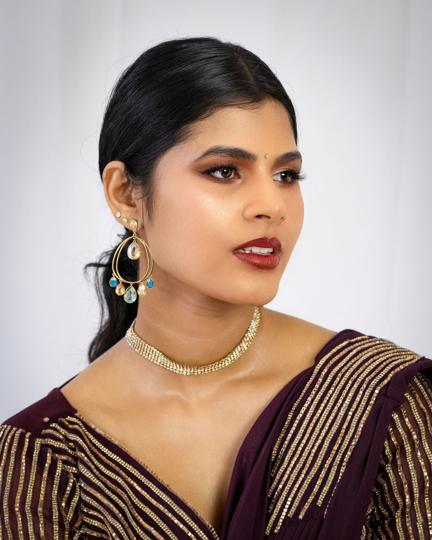 Elegant portrait featuring traditional South Asian jewelry and burgundy embroidered attire. Indian portrait photographer