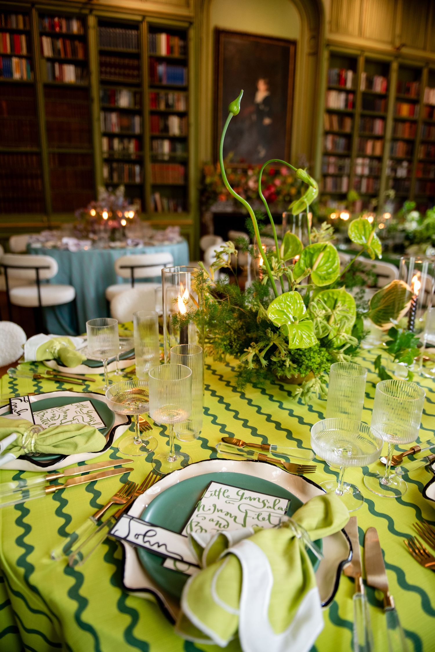 Elegant table setting with green and blue linens, candles, and fresh foliage centerpieces in a library dining room. Meridian House DC