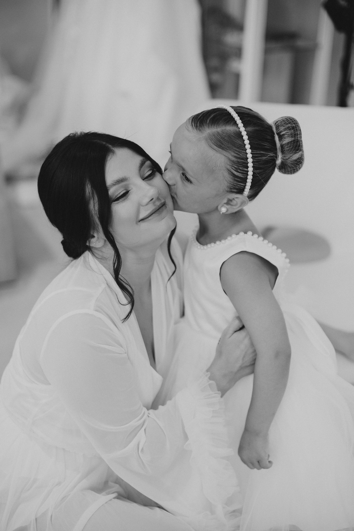 Sweet black and white moment between bride and flower girl during wedding preparations.