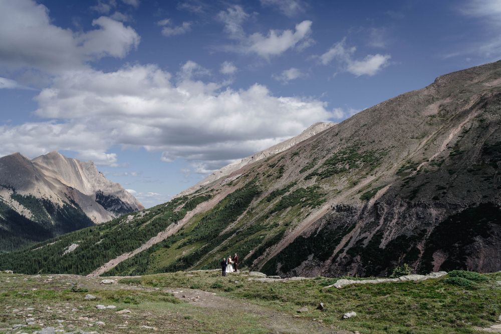 Rockies Heli Canada Weddings, Elopements Scenic mountain landscape with rugged peaks, green slopes and cloudy skies in the Canadian Rockies.