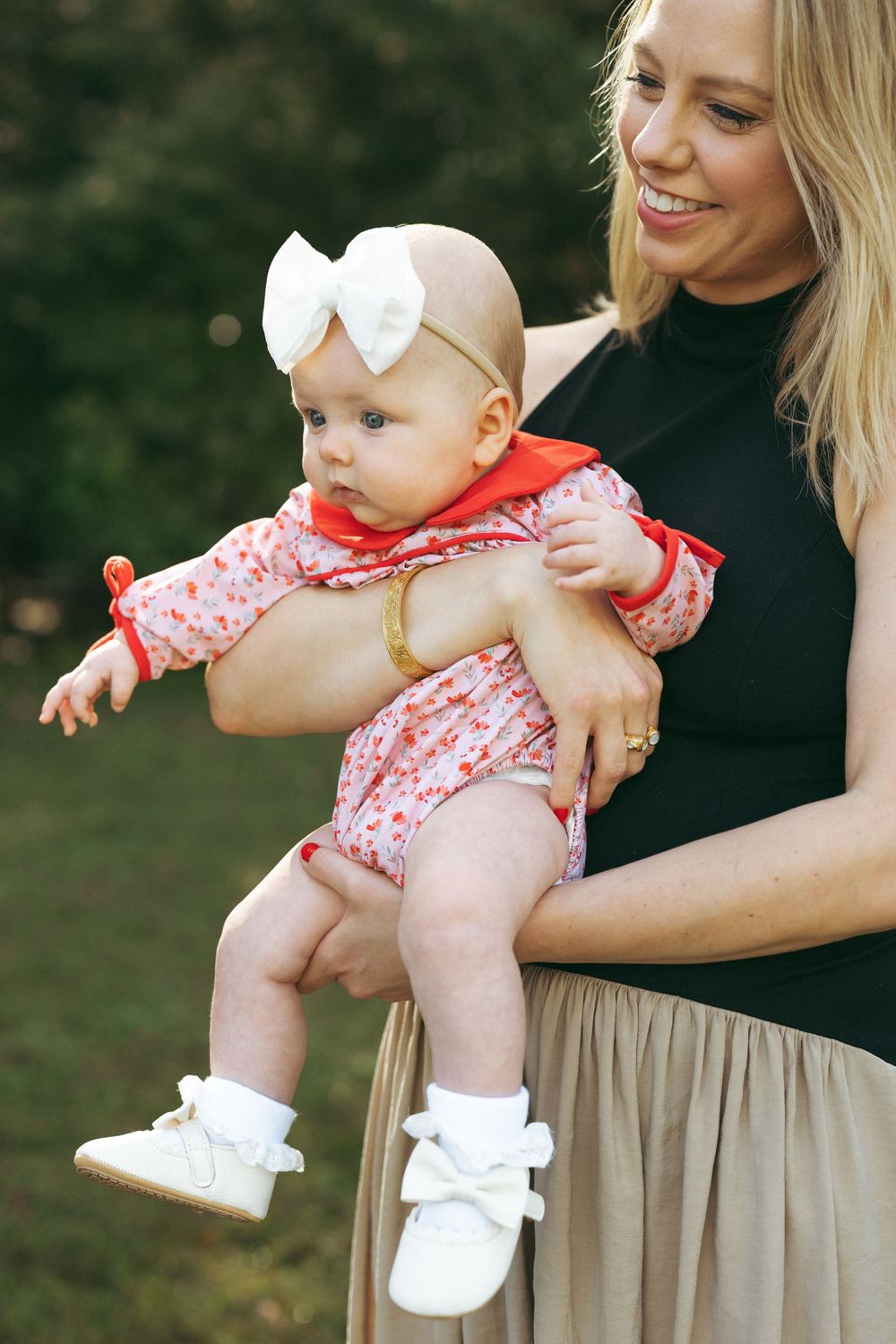 A series of cropped photos showing a baby in a coral-patterned romper and white shoes being held outdoors.