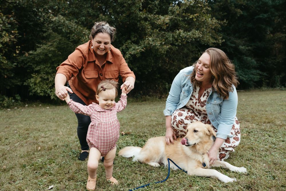 A family and their dog enjoy a playful moment together on the grass during an outdoor photo session.