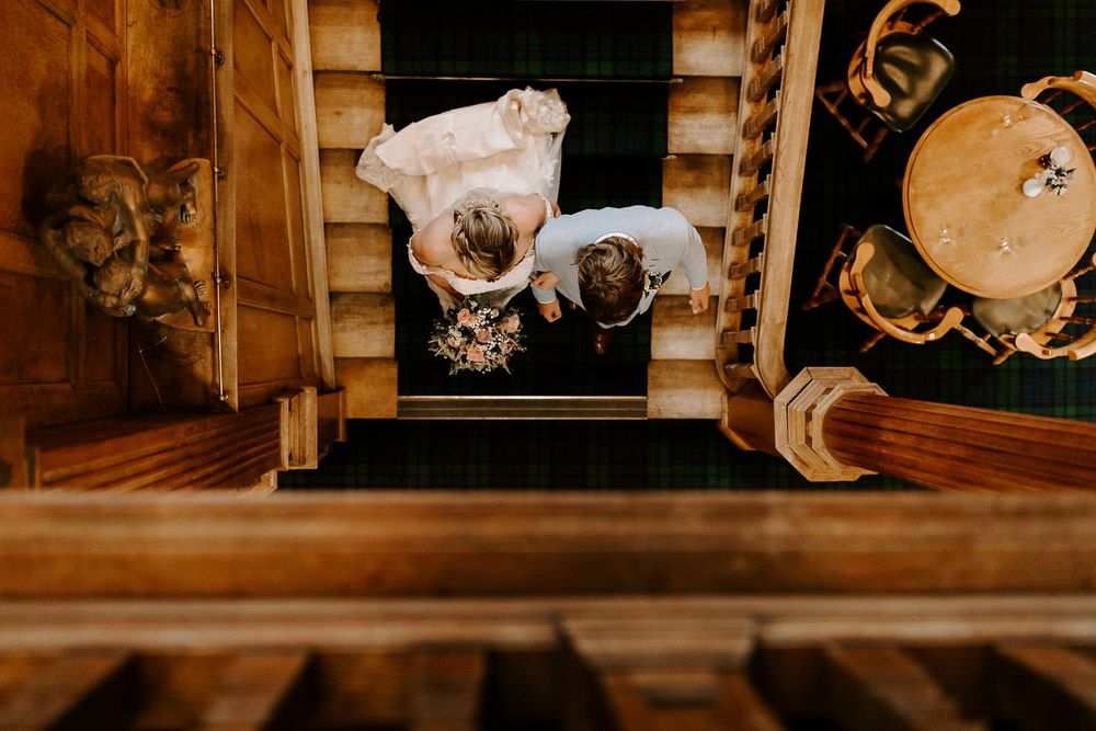 Aerial view looking down a wooden staircase with vintage photographs and decor elements in warm sepia tones.