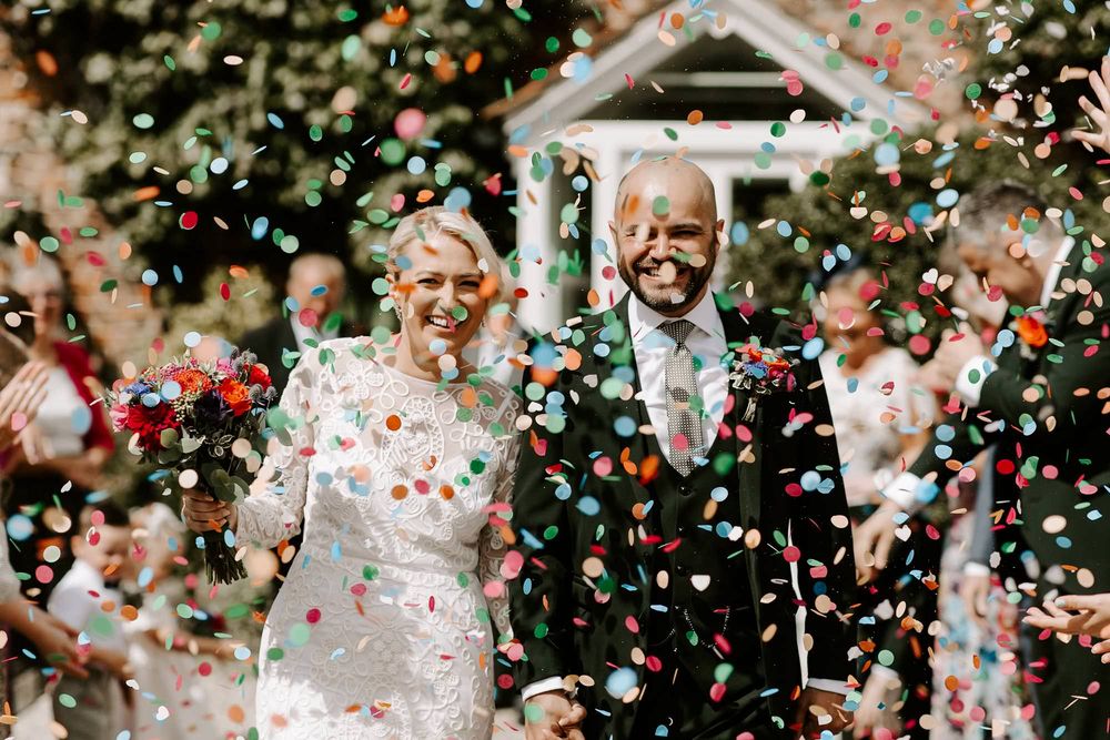 A joyful wedding celebration with confetti raining down on people during an outdoor ceremony.