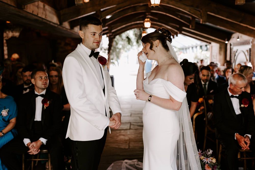 A wedding couple shares an intimate dance moment surrounded by guests at an elegant indoor reception.