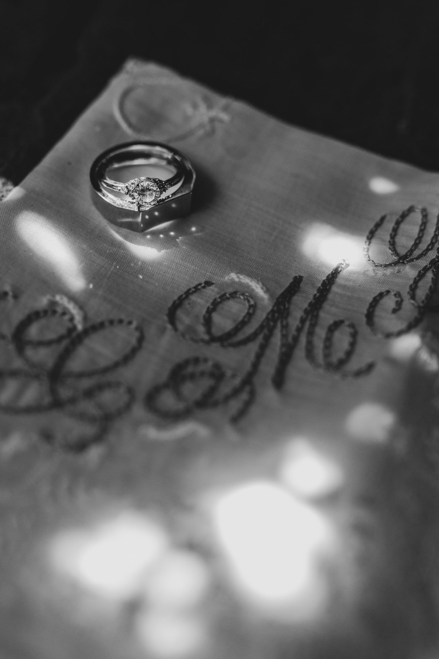 Wedding rings cast shadows on a textured surface in dramatic black and white lighting.
