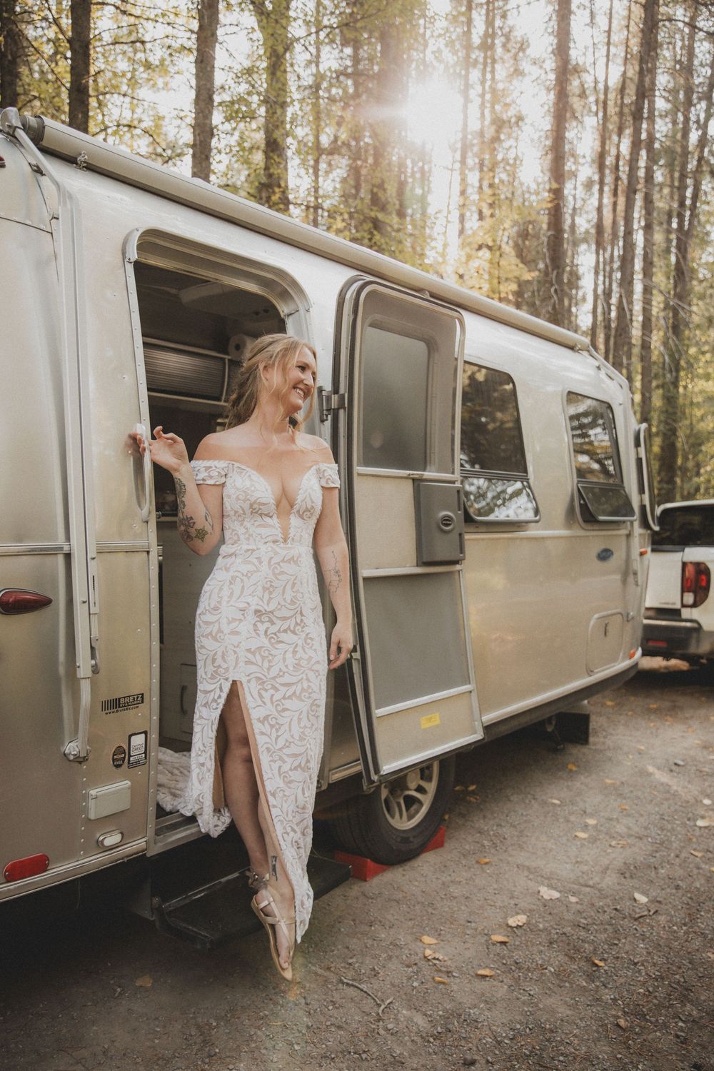 A vintage silver Airstream trailer parked among tall pine trees in a forest setting.
