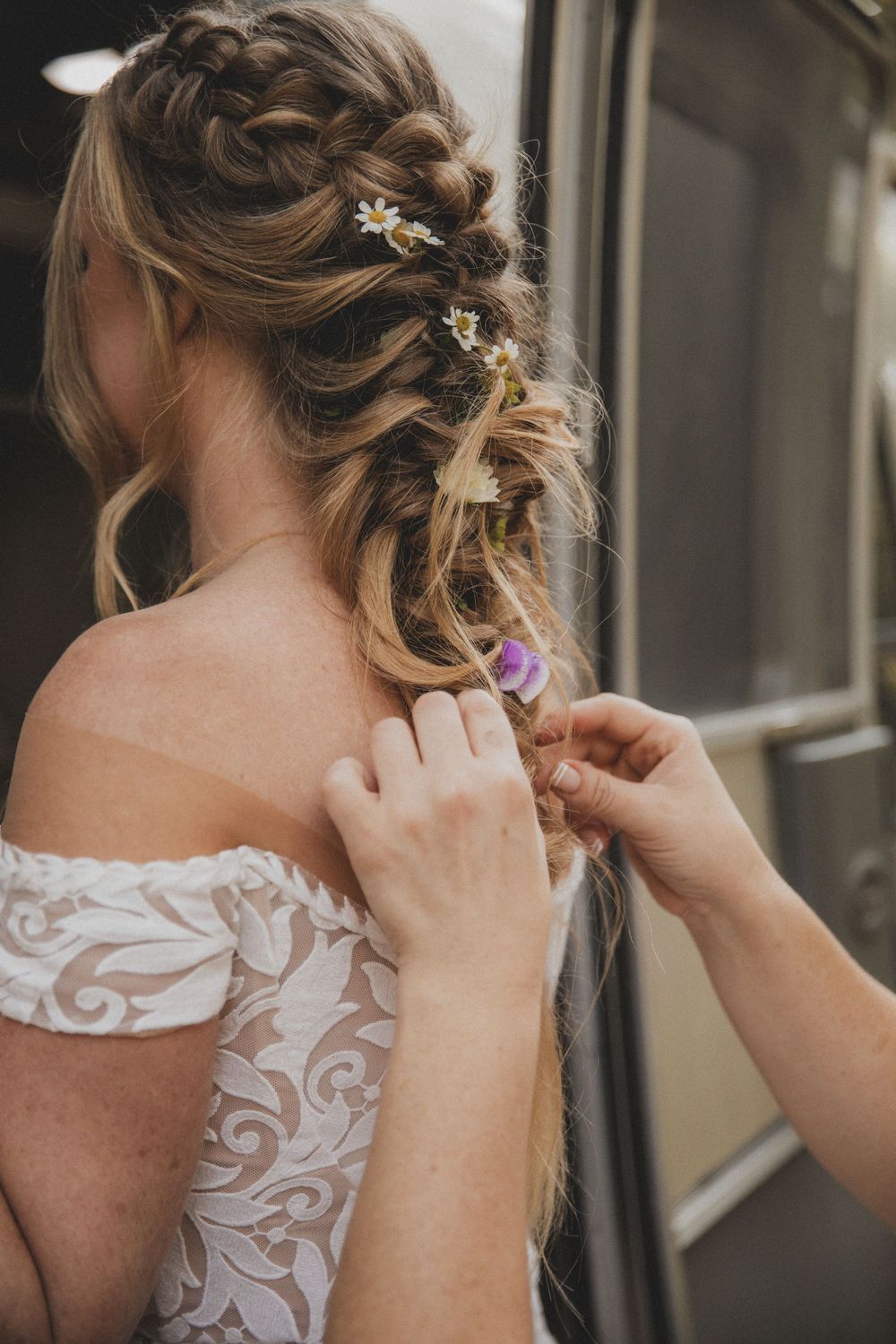 Delicate lace details being adjusted on an off-shoulder wedding dress.