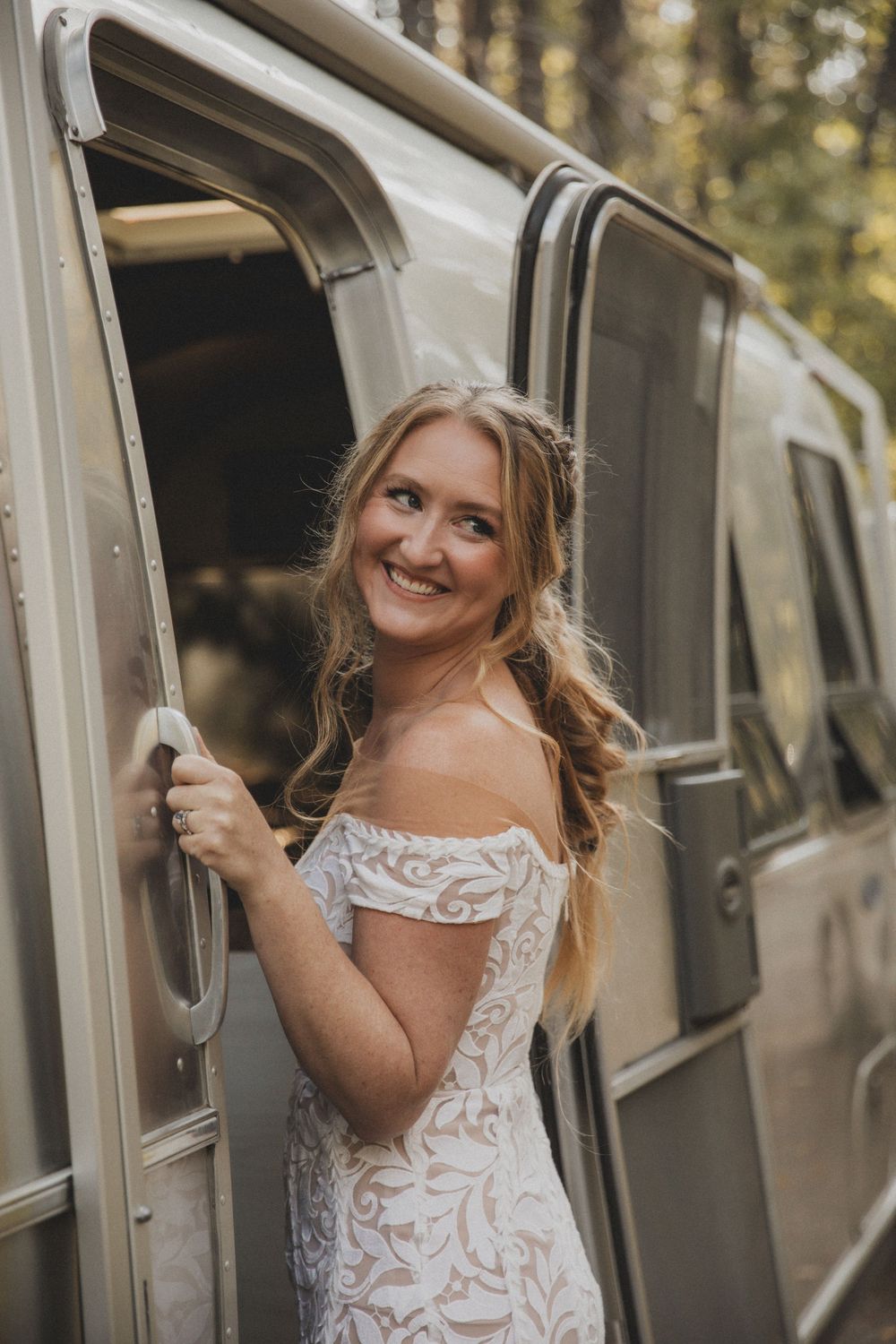 A lace wedding dress detail shown through doorway of vintage Airstream trailer.
