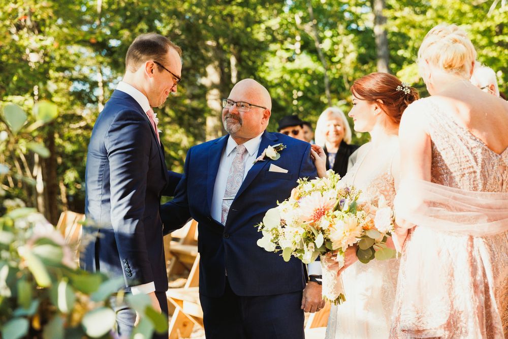 Wedding ceremony moment captured under wooden pergola with floral decorations.