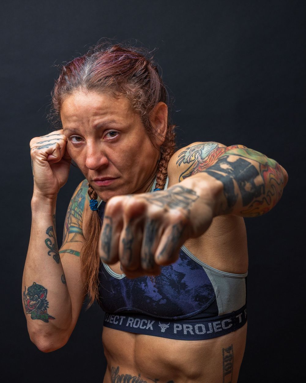 Dynamic boxing poses showing person with tattoos in fighting stance against dark background. photography st louis