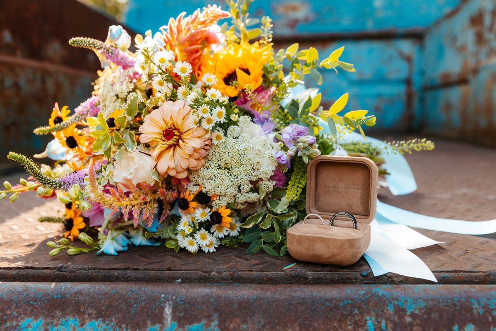 Colorful floral arrangements with orange and yellow blooms displayed on rustic blue surface.wedding photography st louis