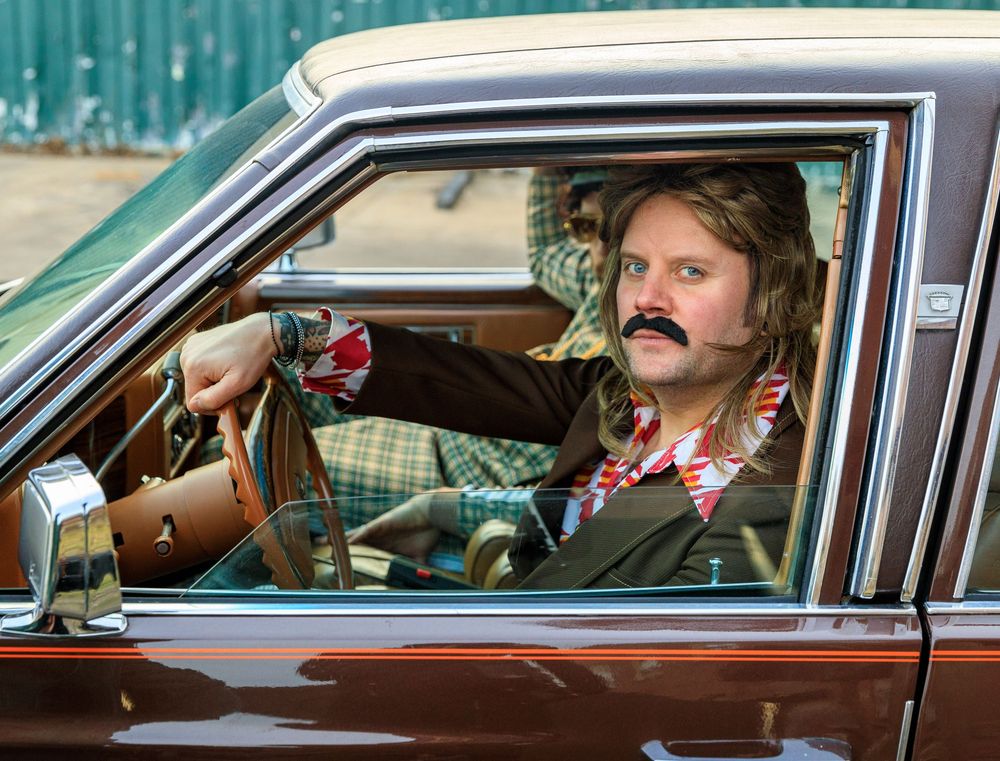 Retro-styled scene of people in vintage car with 70s mustaches and clothing. live event photography st louis.
